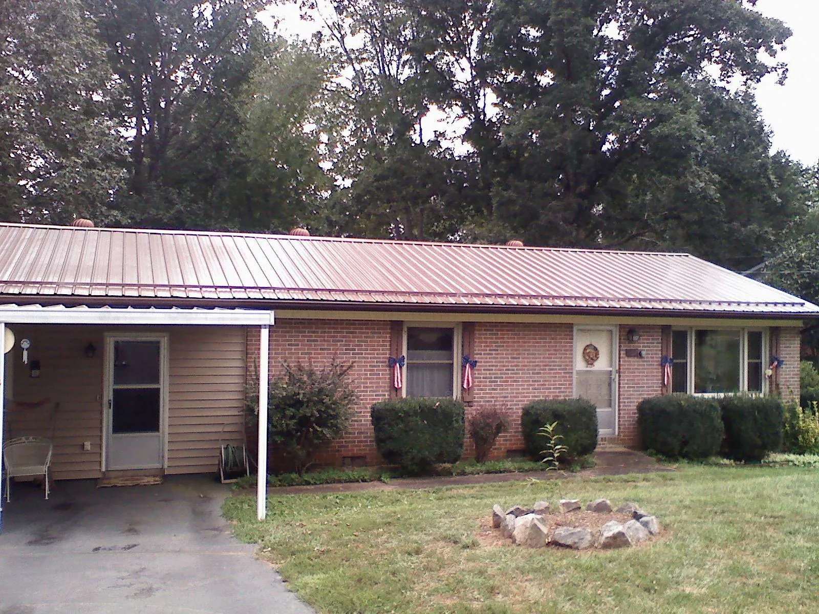 Bronze metal roof and carport on a brick ranch home — Roof Repair work by our crew in Petersburg