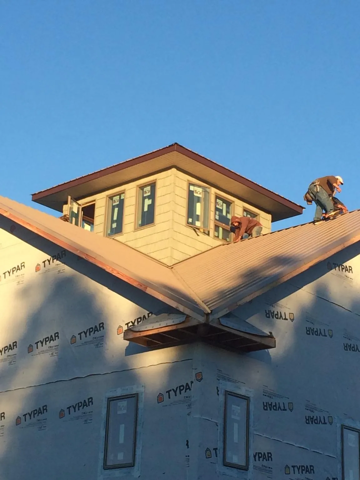 Roofers working around a rooftop cupola on a new metal roof at sunset — Roof Waterproofing in Petersburg by Roofing Brothers